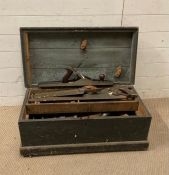 A large vintage wooden tool box containing hand saws, planes etc