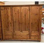 A pine four door, six drawer wardrobe with two mirrors inside in three sections (H194cm W207cm