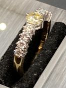 A half eternity style yellow ring, the white head claw set with a central light yellow diamond,