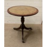 A leather topped pedestal side table on tripod legs with lion paw feet finishing on castors
