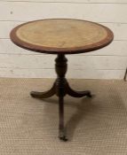 A leather topped pedestal side table on tripod legs with lion paw feet finishing on castors