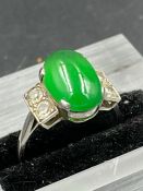 A jade ring with two stone diamond shoulders on a platinum setting Size L