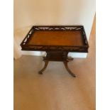 A mahogany galleried side table with brown leather top and brass lion paw feet