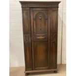 An oak carved hall cupboard on bun feet (H195cm W98cm D47cm)