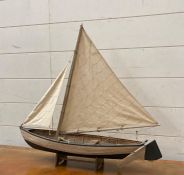 A hand made wooden model of a sailing both on plinth