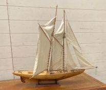 A handmade wooden model of a sailing boat on plinth