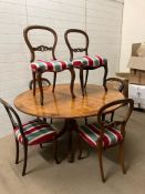 A circular dining table and six mahogany balloon back dining chairs, four matching