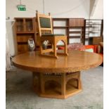 A large circular dining room table with carved edges on an octagonal base with ten dining chairs