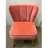 A pink velvet bedroom chair with scalloped edge back