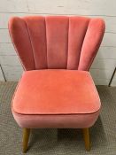 A pink velvet bedroom chair with scalloped edge back