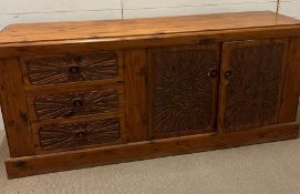 A carved sideboard with drawers one end and cupboard to other (H82cm W189cm D48cm)