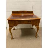 A reproduction correspondence desk with red leather top on claw and ball feet (H90cm W100cm D70cm)