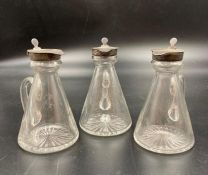 Three silver topped glass jugs, whisky noggins, various hallmarks.