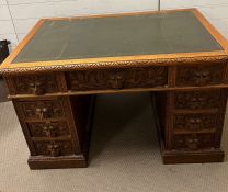 A pedestal desk with carved lion head handles and green leather top (H77cm W122cm D74cm)