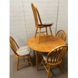 A Mid Century dining table and four stick back chairs (H73cm Dia104cm)