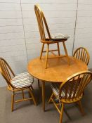 A Mid Century dining table and four stick back chairs (H73cm Dia104cm)