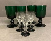 Four green glass wine goblets and five liqueur glasses with twisted stems