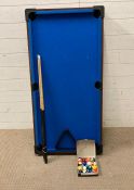 A miniature blue baize pool table with balls and cues