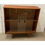A Mid Century free standing bookcase with glazed sliding doors on tapering lrgs (H79cm W76cm D24cm)