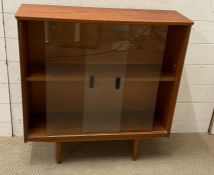 A Mid Century free standing bookcase with glazed sliding doors on tapering lrgs (H79cm W76cm D24cm)