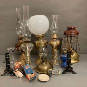 A large selection of vintage oil and gas lamps with accompanying shades and wicks
