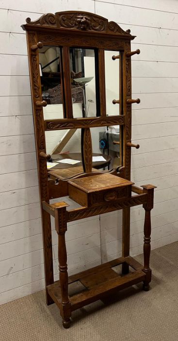 A carved hall stand with turned wooden hooks and mirror plate (H200cm W78cm D37cm)