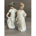 Two Nao figurines, one holding a dog and one holding her dress