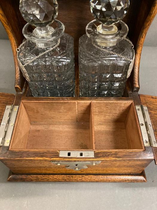 An oak two decanter tantalus with double hinged lids to front to reveal a partitioned storage - Image 4 of 5