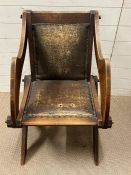 A solid oak Tudor Revival Glastonbury chair, with shaped arms and x frame legs with joints held with