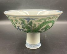 A Chinese blue and white stem bowl with a hand painted green dragon pattern to sides and centre.