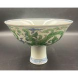 A Chinese blue and white stem bowl with a hand painted green dragon pattern to sides and centre.