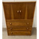 A light oak mid century cupboard with three drawers under (H104cm W77cm D41cm)