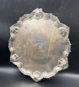 An engraved silver salver on three feet, approx 32cm widest diameter and approximately 950g in