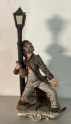 A china hand painted figure of an over refreshed reveler gripping a lamp post, signed