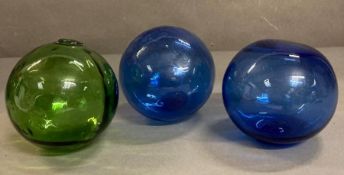 Three vintage glass fishing floats, one green and two cobalt blue