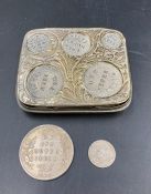 A white metal coin holder for six Indian coins, including a silver Victorian two Anna and a silver