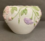 A white planter with purple and pink floral decoration