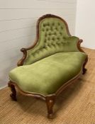 A Victorian button backed chaise longue, upholstered in green with carved floral detail (H93cm