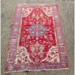 A red ground rug with floral central pattern 220cm x 140cm