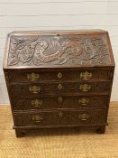 A heavy carved bureau, the fall front enclosing interior fitted drawers and pigeon holes with four