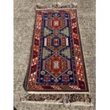 A blue, red and cream rug with diamond pattern to centre 180cm x 76cm