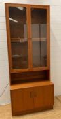 A G-Plan wall unit with two glazed doors and three shelves to top and a two door cupboard to