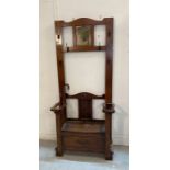 An oak hall stand with six coat hangers, mirror to centre and seat storage under (H185cm W77cm