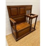 An oak hall stand with panelled seat opening to storage and flanked by a stick stand (H115cm