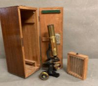 A boxed vintage microscope with glass slides