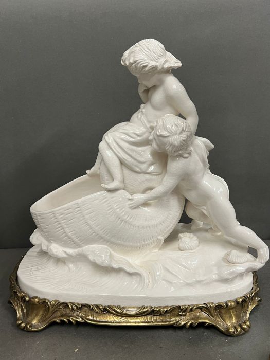 A table centre piece of a cherub pushing a shell into the sea on metal base (H38cm W40cm)