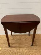 A mahogany side table with drop extending sides and tapering legs terminating on castors (H71cm