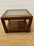 A square coffee table with glass and rattan top