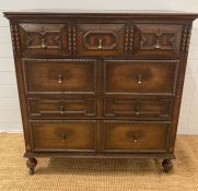 An oak Jacobean style three over three chest of drawers with central drop down front (H110cm