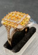 A 9ct gold fashion ring in a cocktail style with yellow and clear stones. Size S1/2
